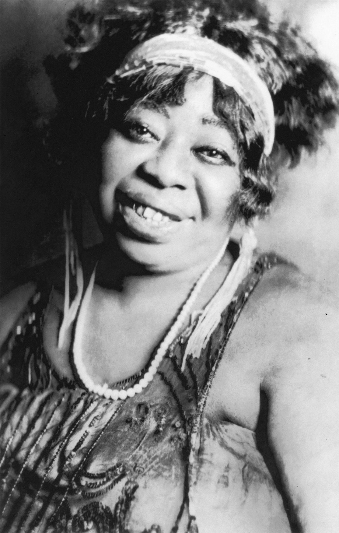 Black and white close up of Ma Rainey, smiling and tilting her head a bit to the right.