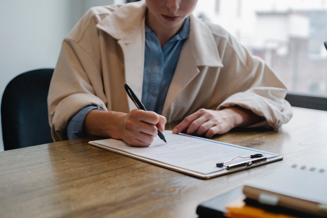 Focused woman writing in clipboard 