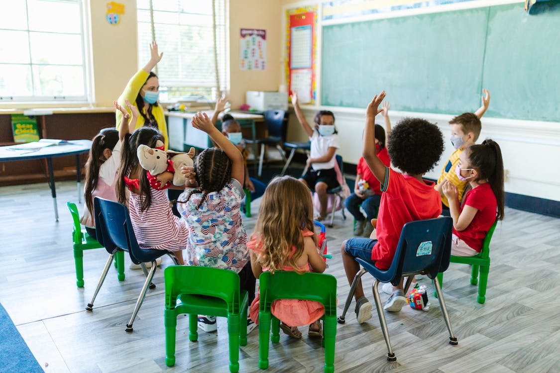 Children Sitting on Chairs Inside the Room