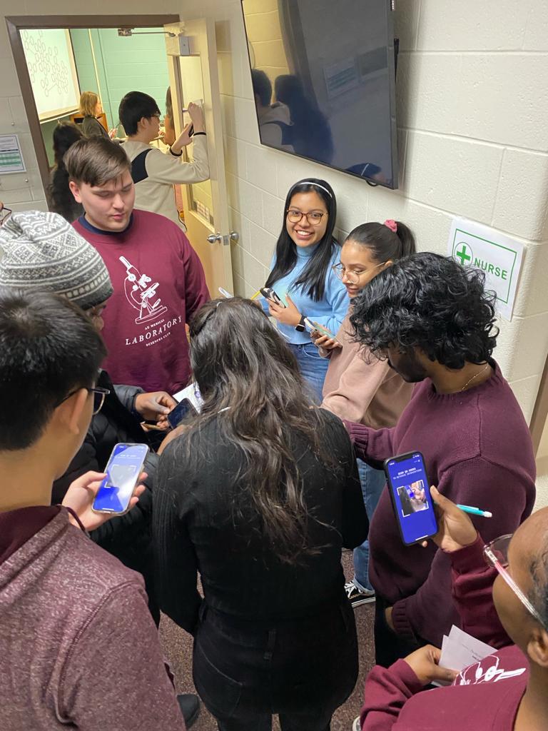 Image of students smiling and looking at their cell phones in a small corridor