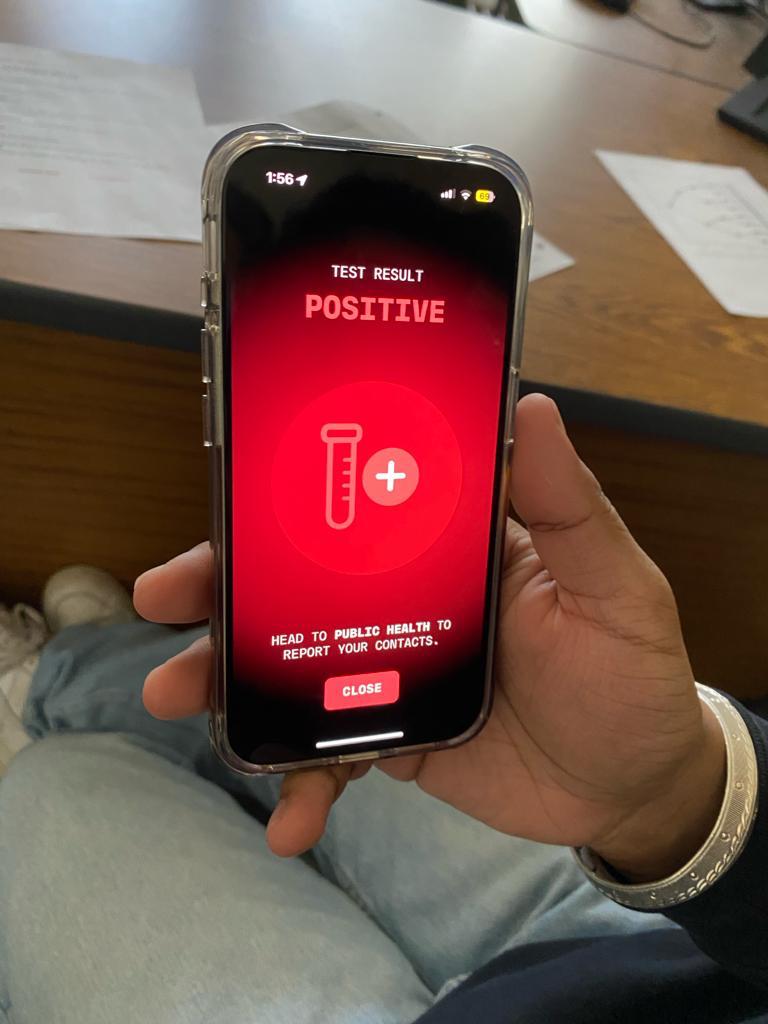 Image of a cell phone showing a red "positive infection" screen